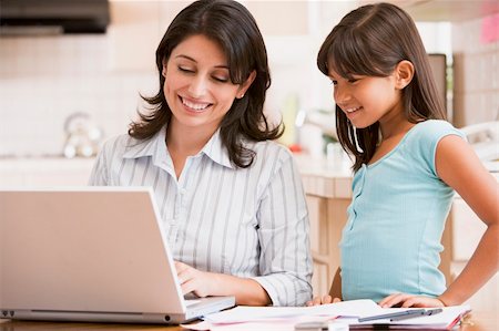 simsearch:400-04044134,k - Woman and young girl in kitchen with laptop and paperwork smilin Fotografie stock - Microstock e Abbonamento, Codice: 400-04044114