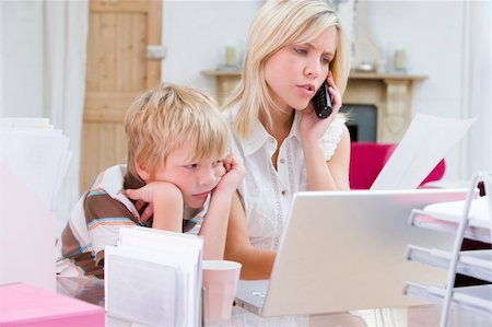 simsearch:400-04044134,k - Woman using telephone in home office with laptop while young boy Fotografie stock - Microstock e Abbonamento, Codice: 400-04044113