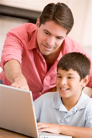 simsearch:400-04044134,k - Man helping young boy in kitchen with laptop smiling Fotografie stock - Microstock e Abbonamento, Codice: 400-04044122