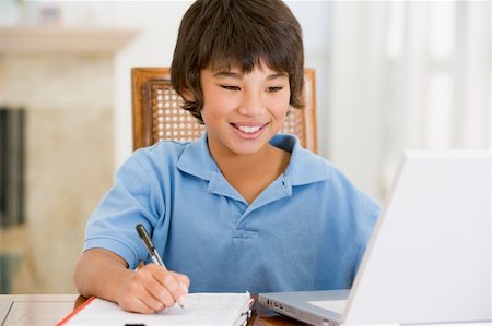 simsearch:400-04044134,k - Young boy with laptop doing homework in dining room smiling Fotografie stock - Microstock e Abbonamento, Codice: 400-04044131