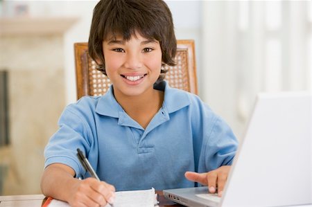 simsearch:400-04044134,k - Young boy with laptop doing homework in dining room smiling Fotografie stock - Microstock e Abbonamento, Codice: 400-04044132