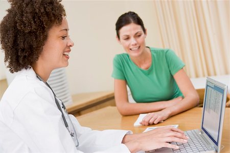 simsearch:400-04021788,k - Doctor using laptop with woman in doctor's office smiling Stock Photo - Budget Royalty-Free & Subscription, Code: 400-04044250