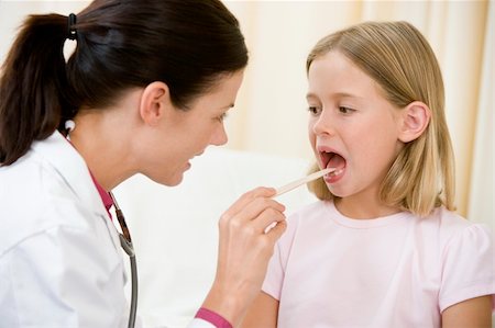 Doctor giving checkup to young girl with tongue depressor in exa Photographie de stock - Aubaine LD & Abonnement, Code: 400-04044303