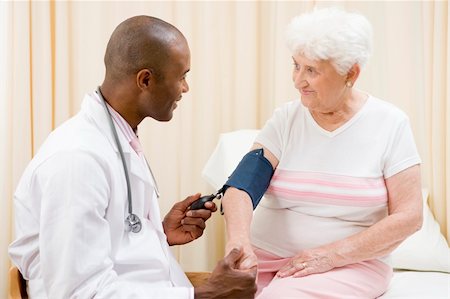 simsearch:400-04021788,k - Doctor checking woman's blood pressure in exam room smiling Stock Photo - Budget Royalty-Free & Subscription, Code: 400-04044314