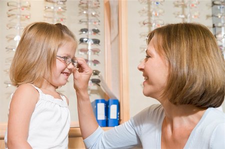 Woman trying eyeglasses on young girl at optometrists smiling Stock Photo - Budget Royalty-Free & Subscription, Code: 400-04044401