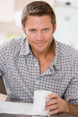 studying drinking coffee - Man in kitchen reading newspaper and smiling Stock Photo - Budget Royalty-Free & Subscription, Code: 400-04044621