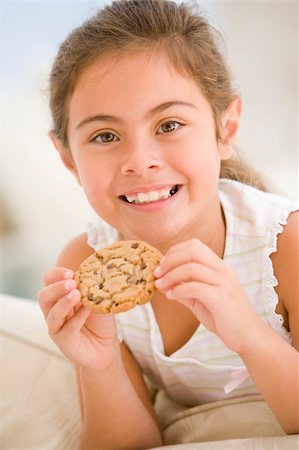simsearch:640-02772614,k - Young girl eating cookie in living room smiling Stock Photo - Budget Royalty-Free & Subscription, Code: 400-04044736