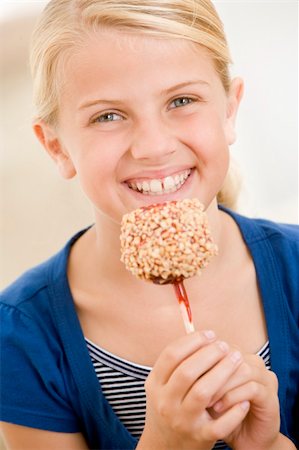 Young girl indoors eating candy apple smiling Stock Photo - Budget Royalty-Free & Subscription, Code: 400-04044771
