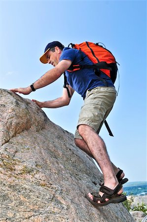 Middle aged man with backpack climbing a rock Stock Photo - Budget Royalty-Free & Subscription, Code: 400-04044862