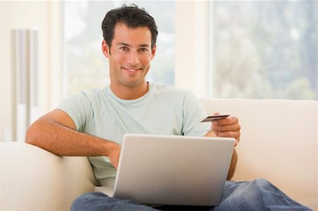 simsearch:400-05000471,k - Man in living room using laptop and holding credit card smiling Foto de stock - Royalty-Free Super Valor e Assinatura, Número: 400-04045113