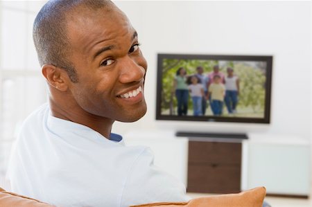 Man in living room watching television smiling Stock Photo - Budget Royalty-Free & Subscription, Code: 400-04045171