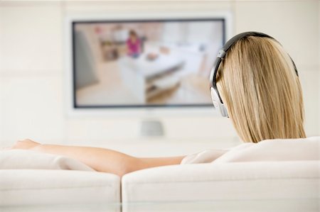 simsearch:400-04045202,k - Woman in living room watching television and wearing headphones Stock Photo - Budget Royalty-Free & Subscription, Code: 400-04045209