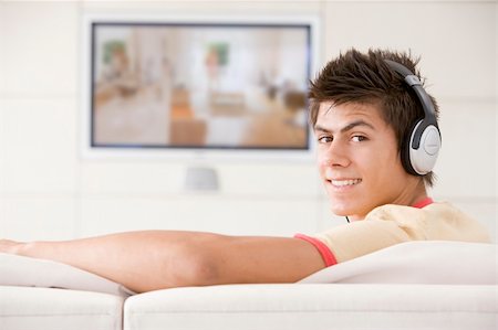 Man in living room watching television and wearing headphones Stock Photo - Budget Royalty-Free & Subscription, Code: 400-04045201