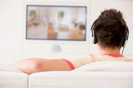 Man in living room watching television and wearing headphones Stock Photo - Budget Royalty-Free & Subscription, Code: 400-04045202