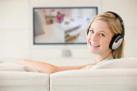 simsearch:400-04045202,k - Woman in living room watching television and wearing headphones Stock Photo - Budget Royalty-Free & Subscription, Code: 400-04045210