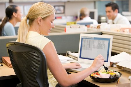 simsearch:689-03124356,k - Businesswoman in cubicle using laptop and eating salad Stock Photo - Budget Royalty-Free & Subscription, Code: 400-04045597