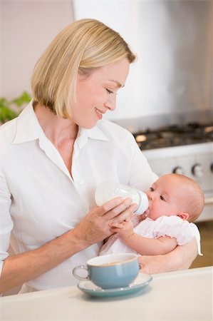 Mother feeding baby in kitchen with coffee smiling Photographie de stock - Aubaine LD & Abonnement, Code: 400-04045927