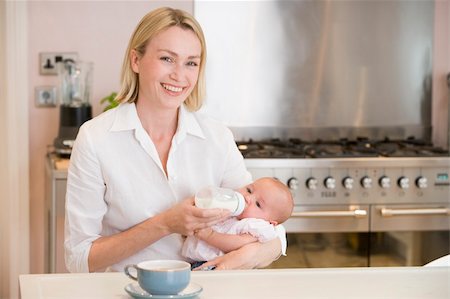 Mother feeding baby in kitchen with coffee smiling Photographie de stock - Aubaine LD & Abonnement, Code: 400-04045929