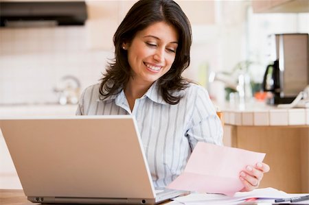 Woman in kitchen with laptop smiling Stock Photo - Budget Royalty-Free & Subscription, Code: 400-04046228