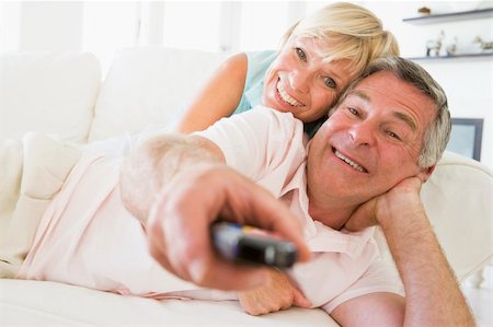 simsearch:400-04046300,k - Couple in living room using remote control smiling Stock Photo - Budget Royalty-Free & Subscription, Code: 400-04046265