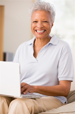 Woman in living room with laptop smiling Stock Photo - Budget Royalty-Free & Subscription, Code: 400-04046289