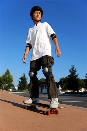 simsearch:400-05260723,k - Boy on a Skateboard Against Blue Sky Looking in the Sun Foto de stock - Super Valor sin royalties y Suscripción, Código: 400-04046332