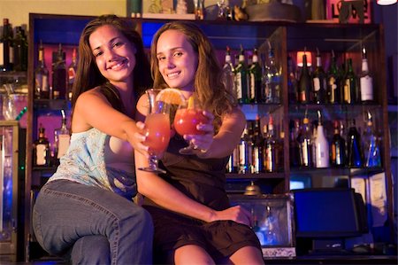 simsearch:400-04040205,k - Two young women sitting on a bar counter, toasting the camera Stock Photo - Budget Royalty-Free & Subscription, Code: 400-04040239