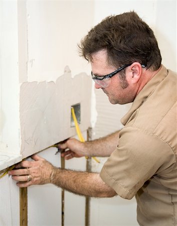 simsearch:400-04494971,k - Electrician installing wiring in an insulated wall.  Focus on electrician.   Authentic and accurate content depiction in accordance with industry code and safety standards. Stock Photo - Budget Royalty-Free & Subscription, Code: 400-04041236