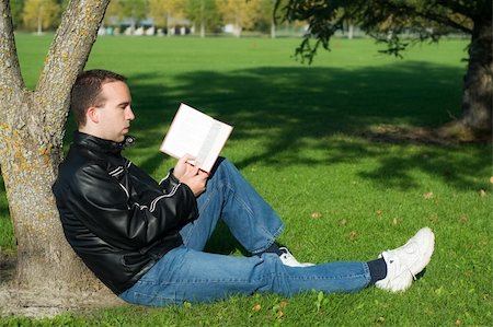 A caucasian man studying a book outside while leaning against a tree Stock Photo - Budget Royalty-Free & Subscription, Code: 400-04042163