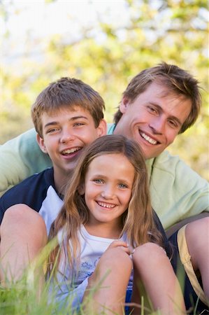 simsearch:400-04042848,k - Man with two children sitting outdoors smiling Fotografie stock - Microstock e Abbonamento, Codice: 400-04042764