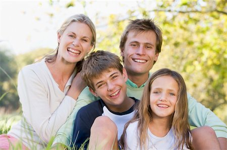 simsearch:400-04042848,k - Family sitting outdoors smiling Fotografie stock - Microstock e Abbonamento, Codice: 400-04042765