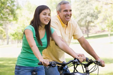 simsearch:400-04402106,k - Man and girl on bikes outdoors smiling Fotografie stock - Microstock e Abbonamento, Codice: 400-04042775