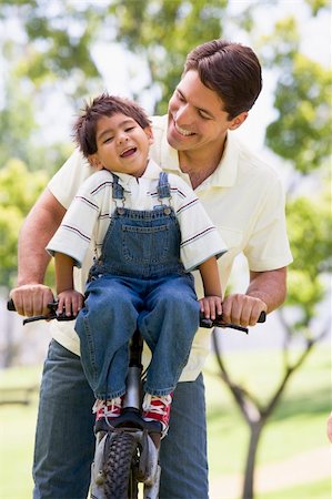 simsearch:400-04402100,k - Man and young boy on a bike outdoors smiling Stock Photo - Budget Royalty-Free & Subscription, Code: 400-04042778
