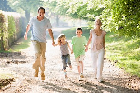 simsearch:400-04042848,k - Family running outdoors holding hands and smiling Fotografie stock - Microstock e Abbonamento, Codice: 400-04042773