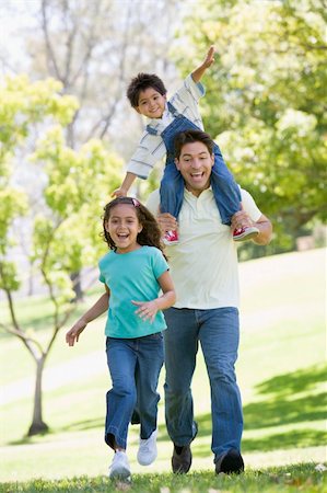 simsearch:400-04042848,k - Man with two young children running outdoors smiling Fotografie stock - Microstock e Abbonamento, Codice: 400-04042782