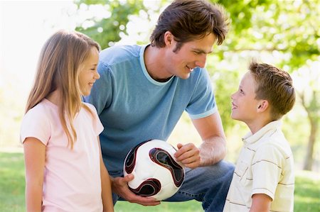 simsearch:400-04042848,k - Man and two young children outdoors holding volleyball and smili Fotografie stock - Microstock e Abbonamento, Codice: 400-04042821