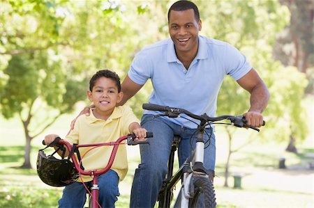 simsearch:400-04402106,k - Man and young boy on bikes outdoors smiling Fotografie stock - Microstock e Abbonamento, Codice: 400-04042837