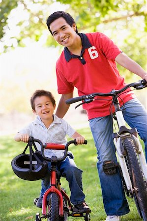 simsearch:400-04402106,k - Man and young boy on bikes outdoors smiling Fotografie stock - Microstock e Abbonamento, Codice: 400-04042863
