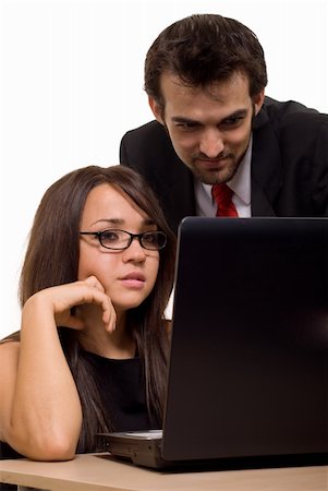 Attractive brunette woman sitting on a desk in front of laptop computer with a man coworker standing behind her both looking at screen Stock Photo - Budget Royalty-Free & Subscription, Code: 400-04043016