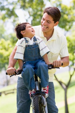 simsearch:400-04402106,k - Man and young boy on a bike outdoors smiling Fotografie stock - Microstock e Abbonamento, Codice: 400-04043047