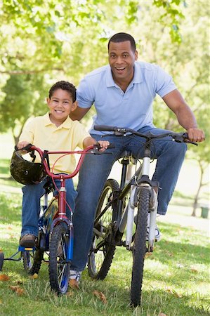 simsearch:400-04402106,k - Man and young boy on bikes outdoors smiling Fotografie stock - Microstock e Abbonamento, Codice: 400-04043053