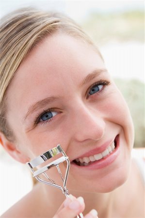 simsearch:400-04043357,k - Woman with eyelash curler smiling Photographie de stock - Aubaine LD & Abonnement, Code: 400-04043344