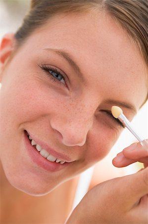 simsearch:400-05734913,k - Woman with eyeshadow applicator smiling Foto de stock - Royalty-Free Super Valor e Assinatura, Número: 400-04043355