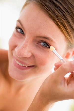 simsearch:400-05734913,k - Woman with eyeshadow applicator smiling Foto de stock - Royalty-Free Super Valor e Assinatura, Número: 400-04043356