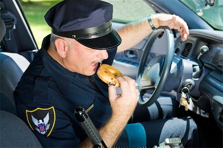 simsearch:400-04559275,k - Police officer in his squad car, taking a bit from a donut. Foto de stock - Super Valor sin royalties y Suscripción, Código: 400-04043504