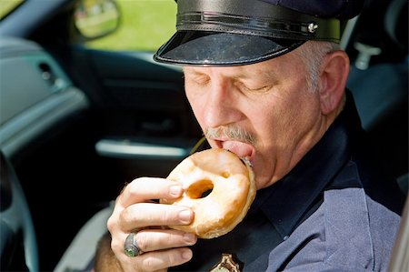 simsearch:400-04559275,k - Police officer biting into a delicious glazed donut. Foto de stock - Super Valor sin royalties y Suscripción, Código: 400-04043501