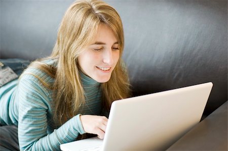 simsearch:400-04999709,k - A young woman relaxed and laying forward on a sofa with her laptop Photographie de stock - Aubaine LD & Abonnement, Code: 400-04043513