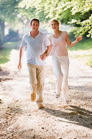 Couple running outdoors holding hands and smiling Stock Photo - Budget Royalty-Free & Subscription, Code: 400-04043591