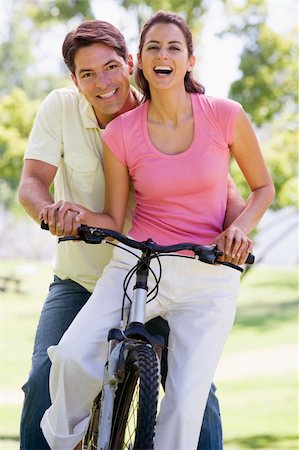 simsearch:400-04402106,k - Couple on a bike outdoors smiling Fotografie stock - Microstock e Abbonamento, Codice: 400-04043603