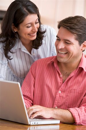 Couple in kitchen using laptop smiling Stock Photo - Budget Royalty-Free & Subscription, Code: 400-04043665